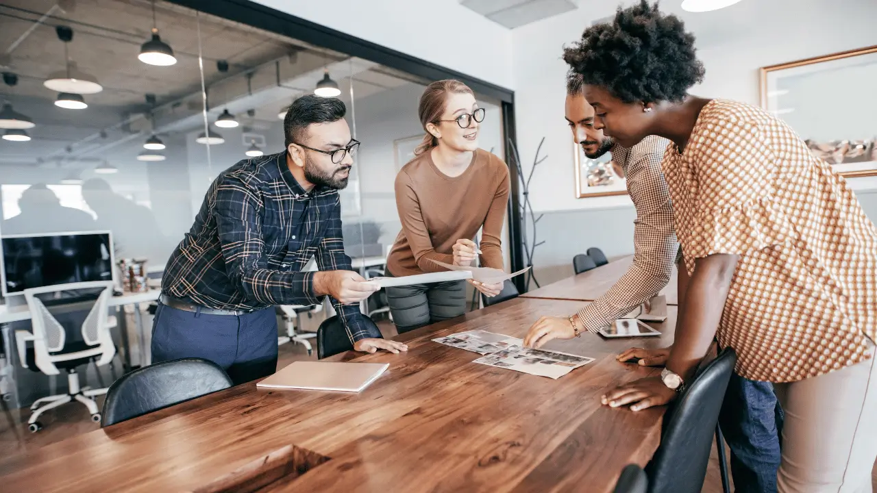 Pessoas em volta de uma mesa, em um ambiente empresarial. São dois homens e duas mulhers.