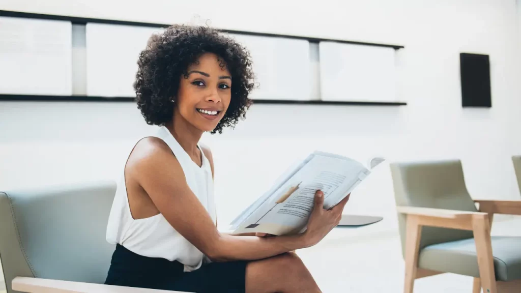 Mulher sorrindo com livro na mão